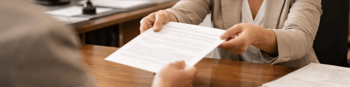 Pessoa entrega um documento a um atendente em um cartório, em um ambiente interno bem iluminado, com enquadramento em plano médio e atmosfera institucional, transmitindo formalidade, confiança e organização no atendimento