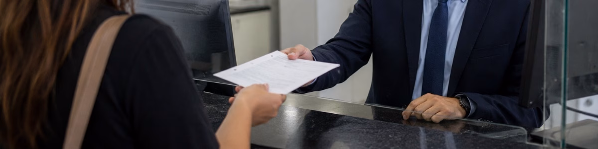 certidão de nascimento RN Funcionário de cartório recebe uma certidão de uma cliente em um balcão de atendimento, em ambiente profissional, organizado e com iluminação suave